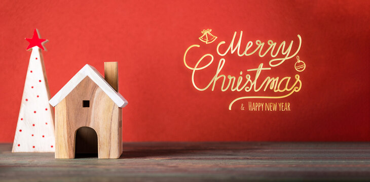 Merry chistmas and happy new year with wooden home wear santa hat on wood table with vivid red background