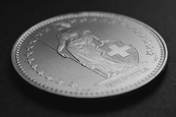 1 Swiss Franc coin closeup. Black and white background or wallpaper about economy, business or taxes. Money and Central Bank in Switzerland. Blurred figure of Helvetia, focus on the cross. Macro