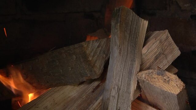Burning firewood in fire-box of fireplace in country cottage. Rustic cooking oven with burning logs