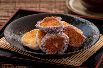 Babin, a simple chewy Thai dessert simply made of glutinous rice flour, coconut flesh, palm sugar, coconut milk and salt and pan grilled on a flat pan. Dark tone.