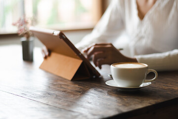 white hot coffee A woman in a white shirt works an orange iPad at a coffee shop in Chiang Mai on 29.9.2022.