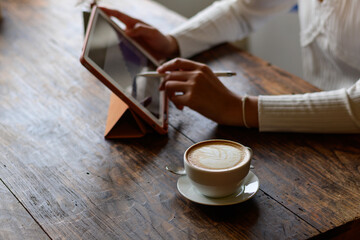 white hot coffee A woman in a white shirt works an orange iPad at a coffee shop in Chiang Mai on 29.9.2022.