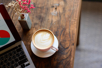 Hot coffee in a white mug with a pair of laptops displayed. Vase of dried flowers come together beautifully. At a coffee shop in Chiang Mai on 29.9.2022