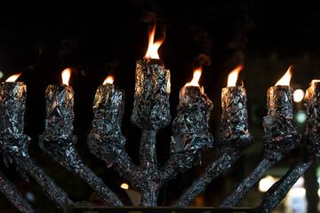 A large, public menorah wrapped in aluminum foil burns on the eighth night of Hanukkah, the...