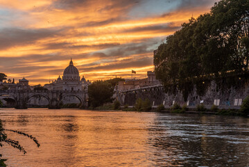Fototapeta premium Panoramic View of the Dome of the Basilic of Saint Peter in Rome beside the Bridge on the Tevere River in Rome at Sunset