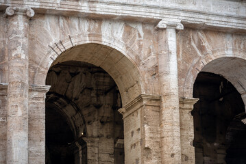Close-up of the arches of the Colosseum with in the background the internal part of the walls soiled by the accumulation of dust of time