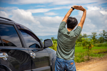 Man driver is stretching after a long road trip drive to relieve her back pain.