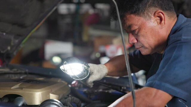 Car mechanic repairing the engine with a wrench, car service A mechanic inspects the engine of an automobile.