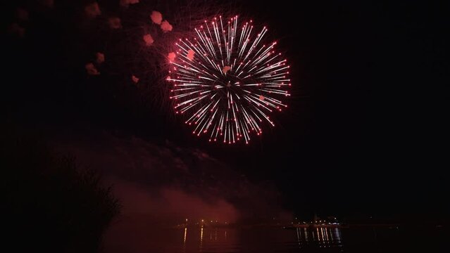 4k footage of beautiful Fireworks on Deep Black Background Sky on Fireworks festival from sail yacht over night city lights in summer river night trip. High quality 4k raw video
