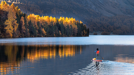 Fototapeta na wymiar On paddleboard in mountain lake in autumn