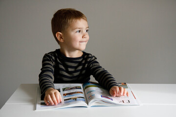 Dziecko czyta - zadanie domowe - odrabianie lekcji - chłopiec uczy się - nauka czytania - pierwszoklasista  - obrazy, fototapety, plakaty