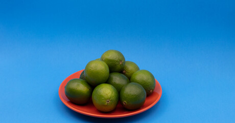 green lemon in orange dish on blue background
