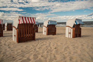Fototapeta na wymiar Wicker roofed beach chairs at the sand beach. Strandkorb at north seashore. 