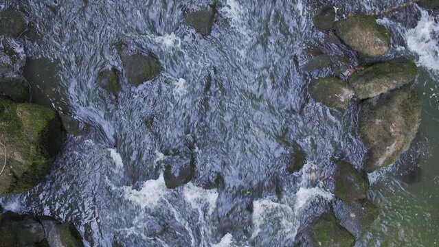 Looking Down on the River with Water Rushing Through the Stones Flying Above Aerial Shot