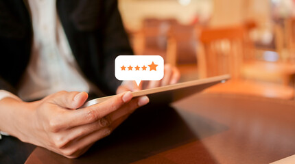 close up on customer man hand pressing on tablet screen with gold five star rating feedback icon...