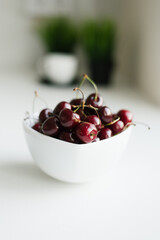 Ripe cherry on a white plate is in the kitchen