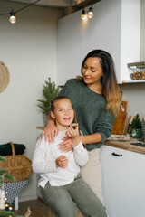 Happy family mother and child daughter taste Christmas cookies in the kitchen in the house