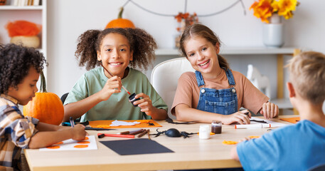 Happy multinational group of children making Halloween home decorations together