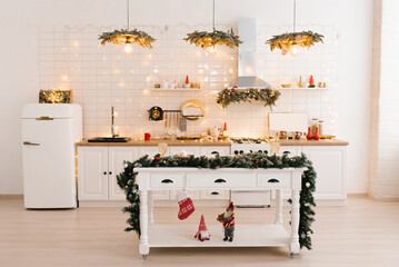 Christmas decor. Bright white kitchen interior with bright garlands and Christmas wreaths.