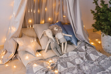 Children's room in pastel shades of gray and blue with a fabric tent, toys and pillows with Christmas lights