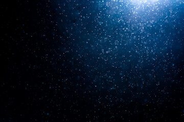 Blue particles on black background with cinematic atmosphere. Glittering sparkling bokeh overlay with copy space for text. - obrazy, fototapety, plakaty