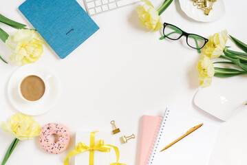 Flat workspace of a lady blogger or freelancer with a notepad and yellow tulips and an office on a white table with a copy space