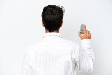 Young man holding a engagement ring isolated on white background in back position