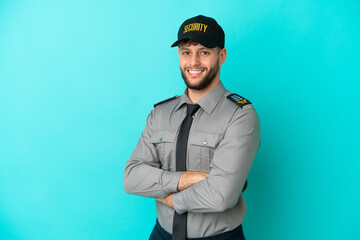 Young security man isolated on blue background with arms crossed and looking forward