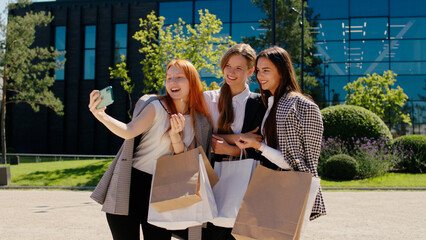 Charismatic and attractive with a large smile group of women taking some selfies in a sunny day after a good shopping beside the shopping centre