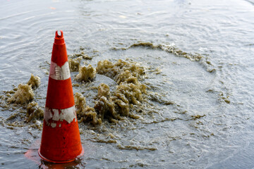 Drain after severe spring storm on flooded street. Sewage overflow on pavement during rain
