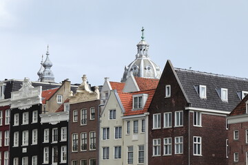 Amsterdam Damrak Canal Historic House Facades with Church Towers in the Background Close Up, Netherlands