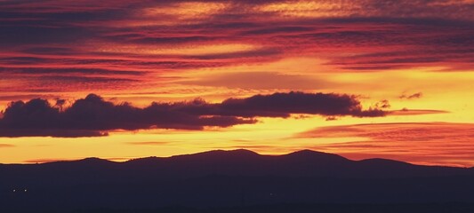 Fototapeta na wymiar Atardecer en la Sierra de Guadarrama en Madrid, España. Cielo anaranjado con los últimos rayos de sol destacando la silueta de las montañas situadas al norte de Madrid.