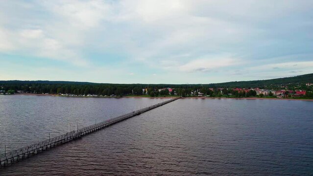 Aerial view during the summer evening. Descending to the pier at Lake Siljan, people walk on the promenade. View of the beach, camping and the town Rättvik, mountain with forests in Dalarna Sweden.