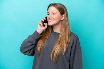 Fototapeta premium Young caucasian woman isolated on blue background keeping a conversation with the mobile phone