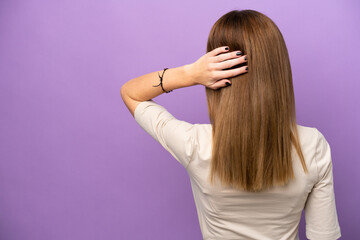 Young English woman isolated on purple background in back position and thinking