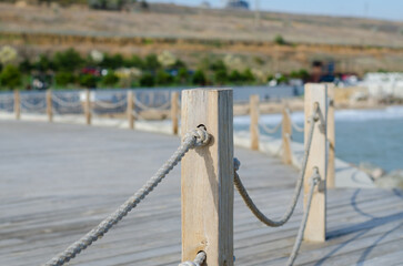 Obraz premium Wooden platform on the seashore. Fence made of old marine rope. Rope knot. Wooden poles. Yacht mooring.