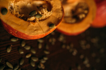 two halves of a pumpkin in close-up on a table strewn with seeds