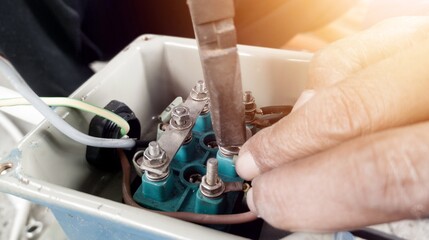 an Electrician Connecting the cable terminals power induction  three phase motor.