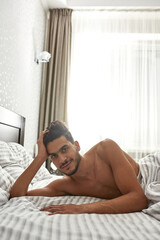 Young middle eastern man resting on bed at home