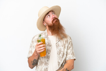 Redhead man with long beard drinking a cocktail on a beach isolated on white background and looking up