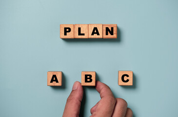 Hand holding B wording on wooden cube block for backup plan selection of business planing concept.