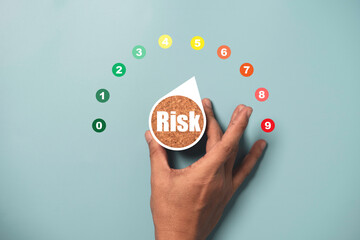 Hand turning risk level indicator rating print screen wooden cube block since low to high on blue background for Risk management and assessment concept.