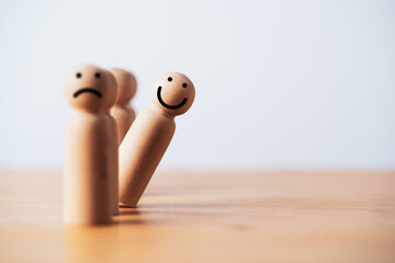 smile face on wooden figure out of line from sad face with copy space for positive mindset...
