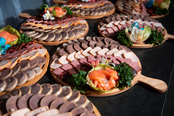 appetizing cold cuts of sausages, kazy, and bacon on a wooden tray