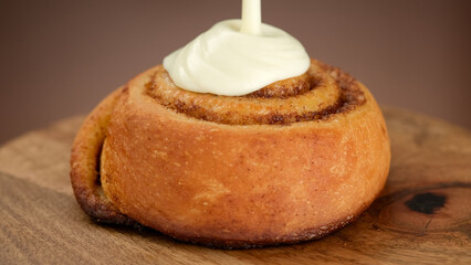 Pouring cream sauce on cinnamon bun. Cinnamon rolls or Cinnabon  