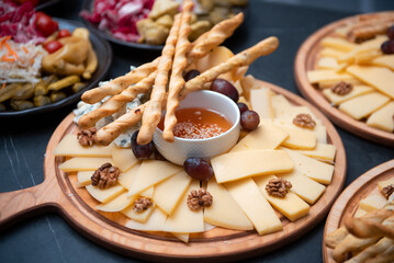 Plate with cheese slices, nuts, bread sticks and honey