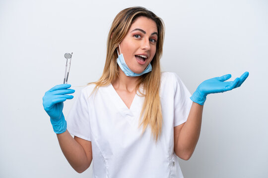 Dentist woman holding tools isolated on white background with shocked facial expression