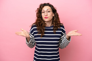 Young caucasian woman isolated on pink background having doubts while raising hands
