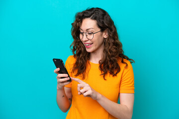 Young caucasian woman isolated on blue background sending a message or email with the mobile