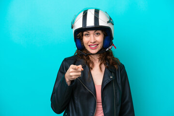 Young caucasian woman with a motorcycle helmet isolated on blue background surprised and pointing front